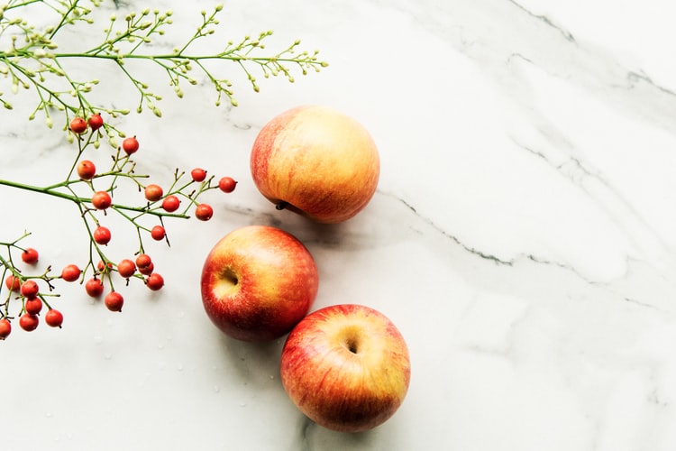 Photo de pommes bio posées sur une table en marbre